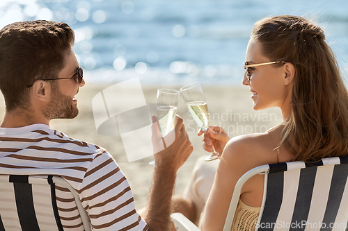 Image of happy couple drinking champagne on summer beach