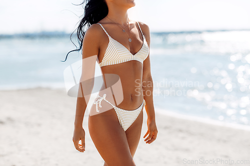 Image of body of young woman in bikini swimsuit on beach