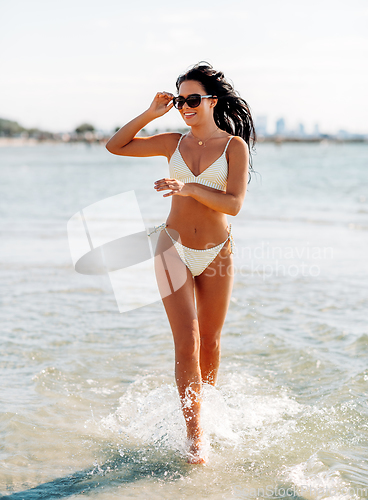 Image of smiling young woman in bikini swimsuit on beach