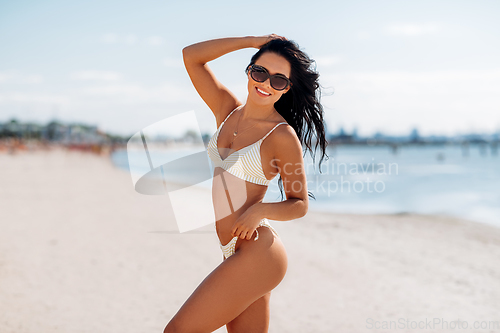 Image of smiling young woman in bikini swimsuit on beach
