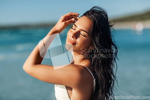 Image of smiling young woman in bikini swimsuit on beach