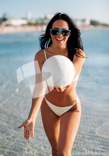 Image of woman in bikini playing with volleyball on beach