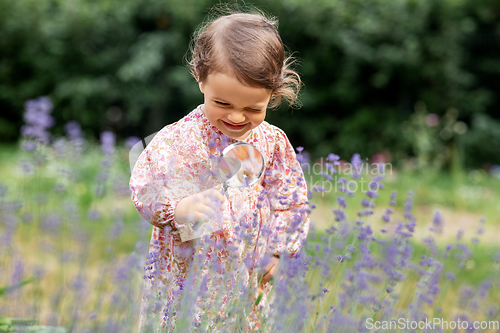 Image of baby girl with magnifier looking at garden flowers