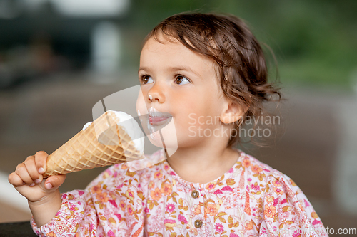 Image of happy little baby girl eating ice cream