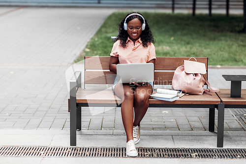 Image of african student girl in headphones with laptop