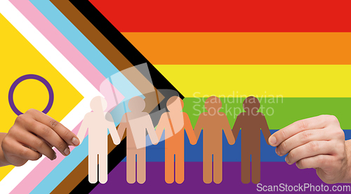 Image of hands holding people pictogram over pride flag