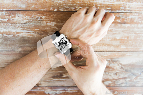 Image of male hands with qr code on smart watch