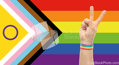 Image of hand with gay pride rainbow wristband shows peace