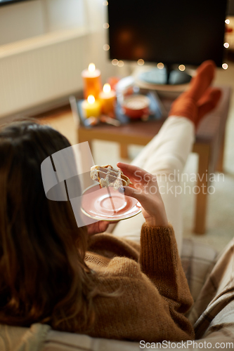 Image of woman watching tv and eating waffle on halloween