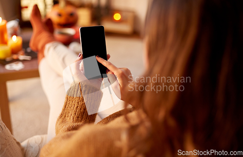 Image of woman using smartphone at home on halloween