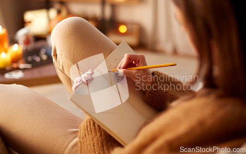 Image of woman writing to diary at home on halloween