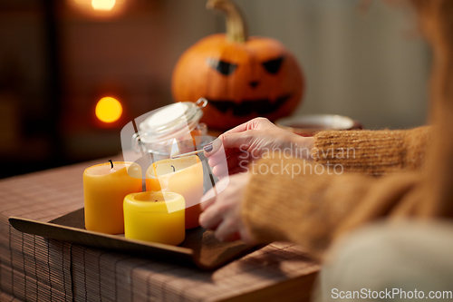 Image of hand with match lighting candle on halloween