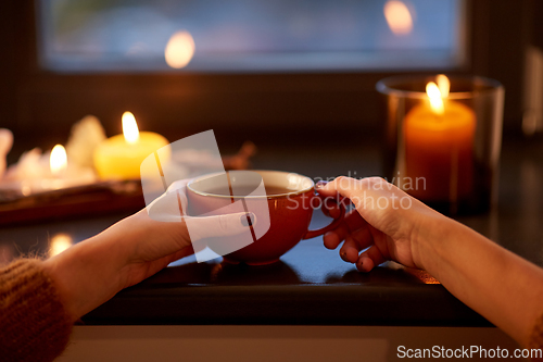 Image of hands with cup of tea on window sill in autumn