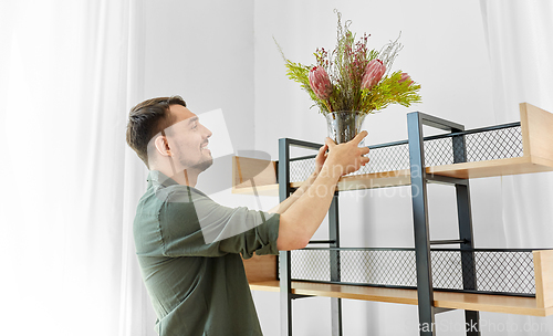 Image of man decorating home with flowers in vase