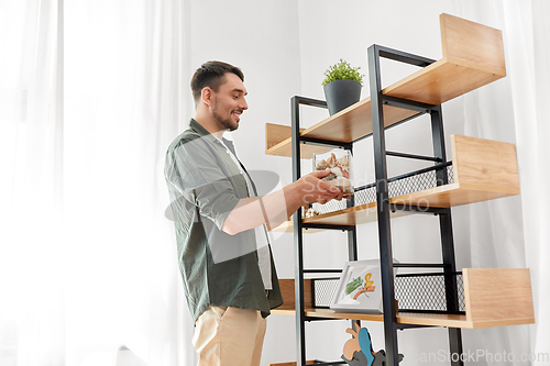 Image of man decorating home with seashells in vase