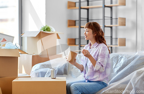 Image of happy woman moving to new home and eating wok