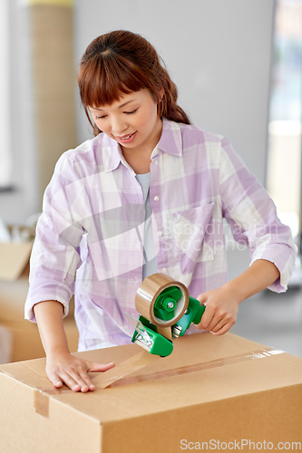 Image of woman with adhesive tape packing box at new home