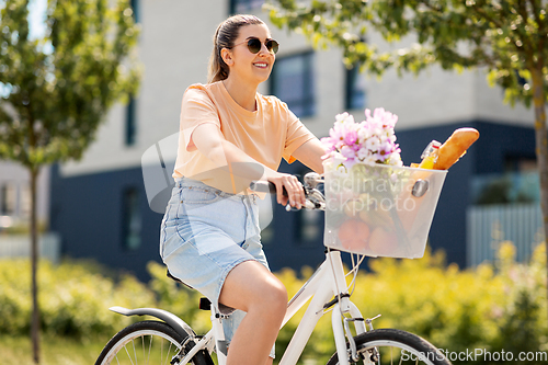 Image of woman with food and flowers in bicycle basket