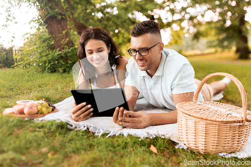 Image of happy couple with tablet pc at picnic in park