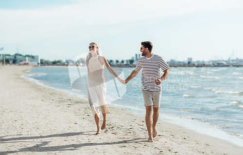 Image of happy couple running along summer beach