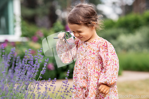 Image of baby girl with magnifier looking at garden flowers