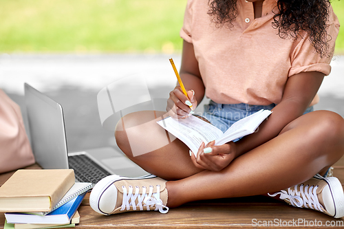 Image of african american student girl making notes in book