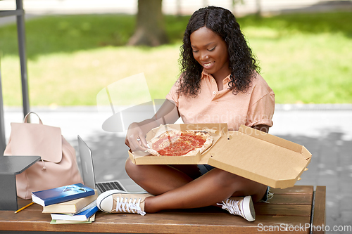 Image of african student girl eating takeaway pizza in city