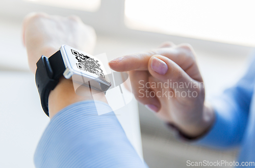 Image of woman's hands with qr code on smart watch