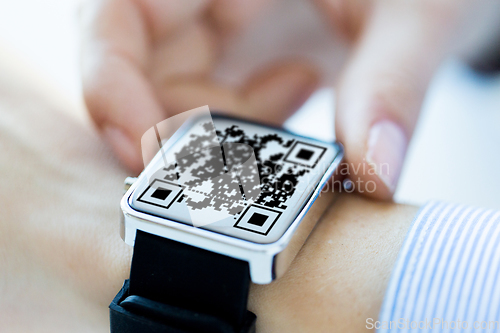 Image of woman's hands with qr code on smart watch