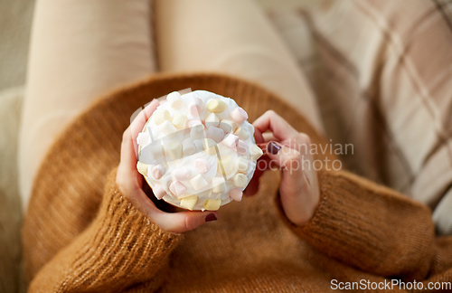 Image of woman holding mug of marshmallow and whipped cream