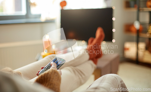 Image of young woman watching tv at home on halloween