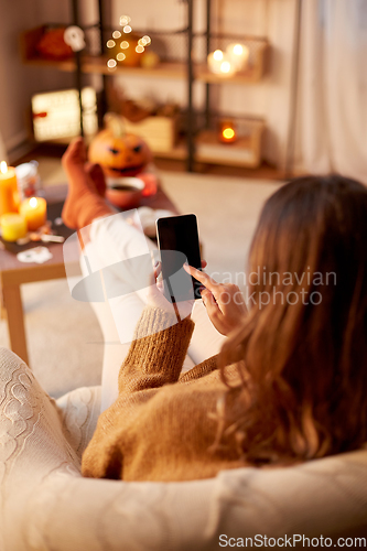Image of woman using smartphone at home on halloween