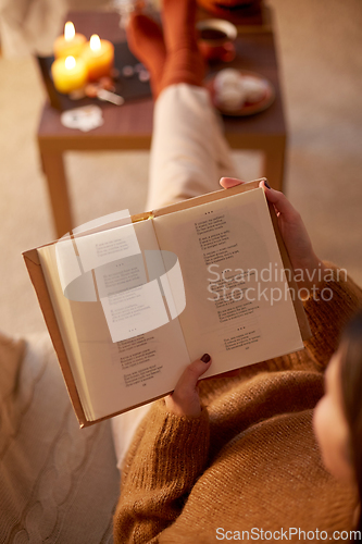 Image of young woman reading book at home on halloween