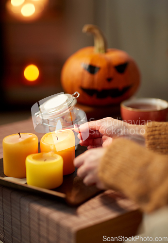 Image of hand with match lighting candle on halloween