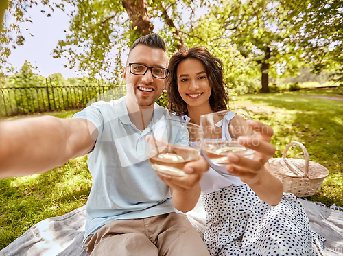 Image of couple drinking wine and taking selfie at park