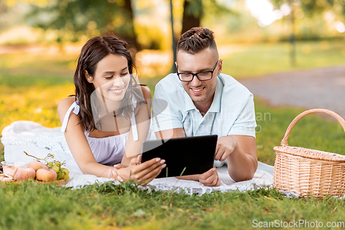 Image of happy couple with tablet pc at picnic in park