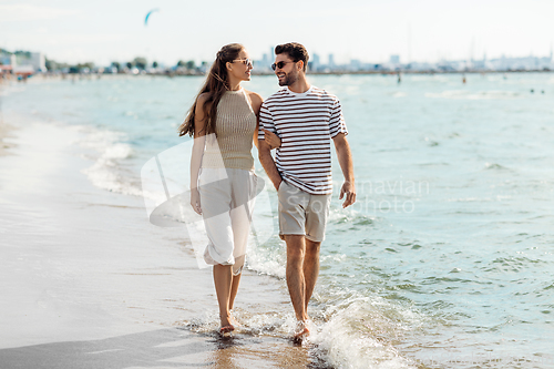 Image of happy couple walking along summer beach