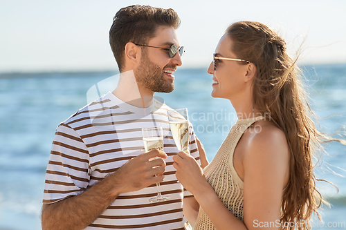 Image of happy couple drinking champagne on summer beach