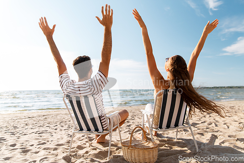 Image of happy couple sitting in folding chairs on beach