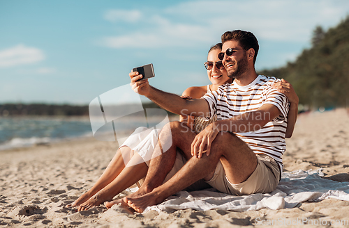 Image of happy couple taking selfie by smartphone on beach