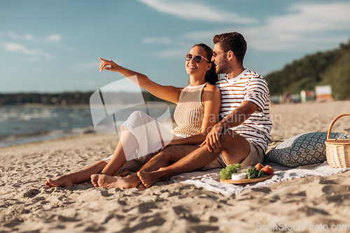 Image of happy couple with food having picnic on beach