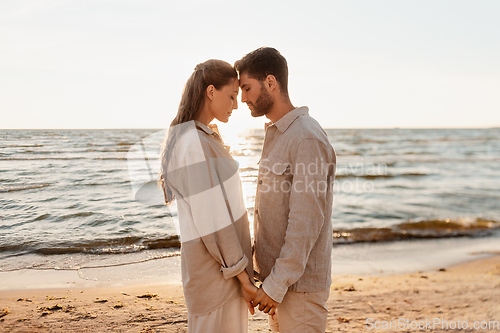 Image of happy couple holding hands on summer beach