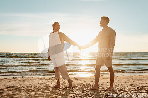 Image of happy couple holding hands on summer beach