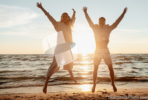 Image of happy couple jumping on summer beach