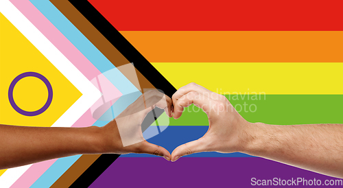 Image of couple showing hand heart over progress pride flag