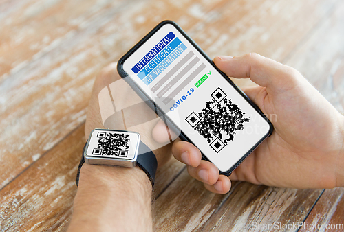 Image of hands with virtual immunity passport on smartphone