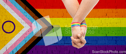 Image of gay couple hands with over progress pride flag