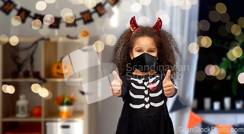 Image of girl in black mask and halloween costume of devil