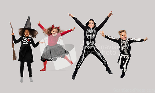 Image of happy children in halloween costumes jumping