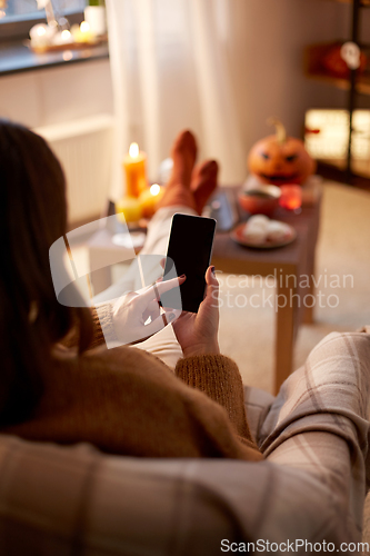 Image of woman using smartphone at home on halloween